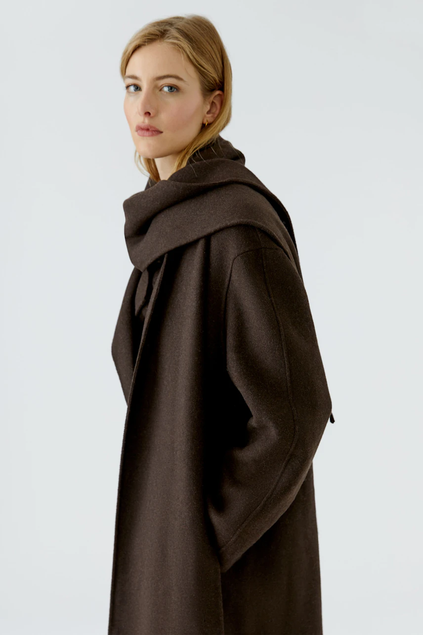 Woman in a brown winter coat, looking confidently. The coat is warm and stylish, perfect for cold days.
