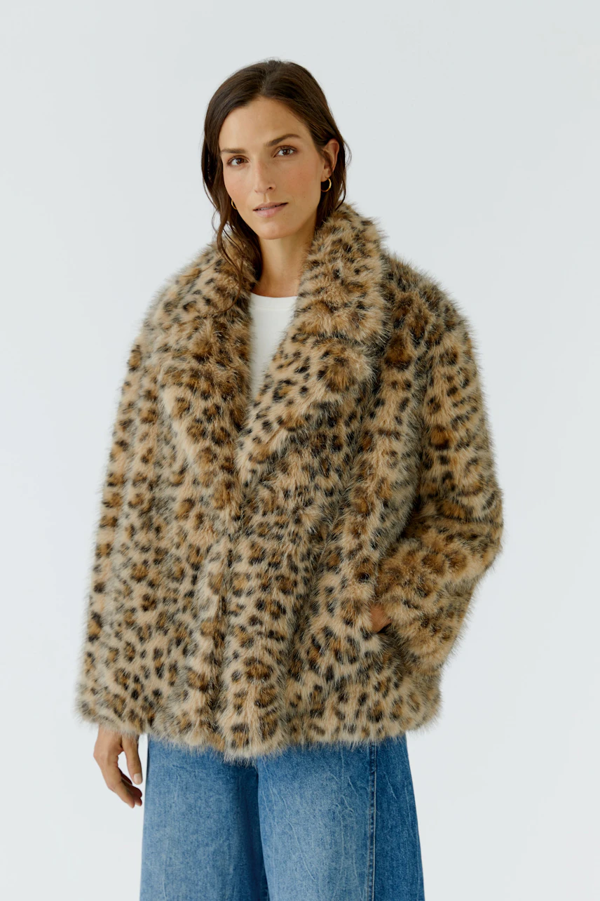 Outdoorjacke: Frau in lässiger, gemusterter Jacke mit Leopardenmuster und blauer Jeans.