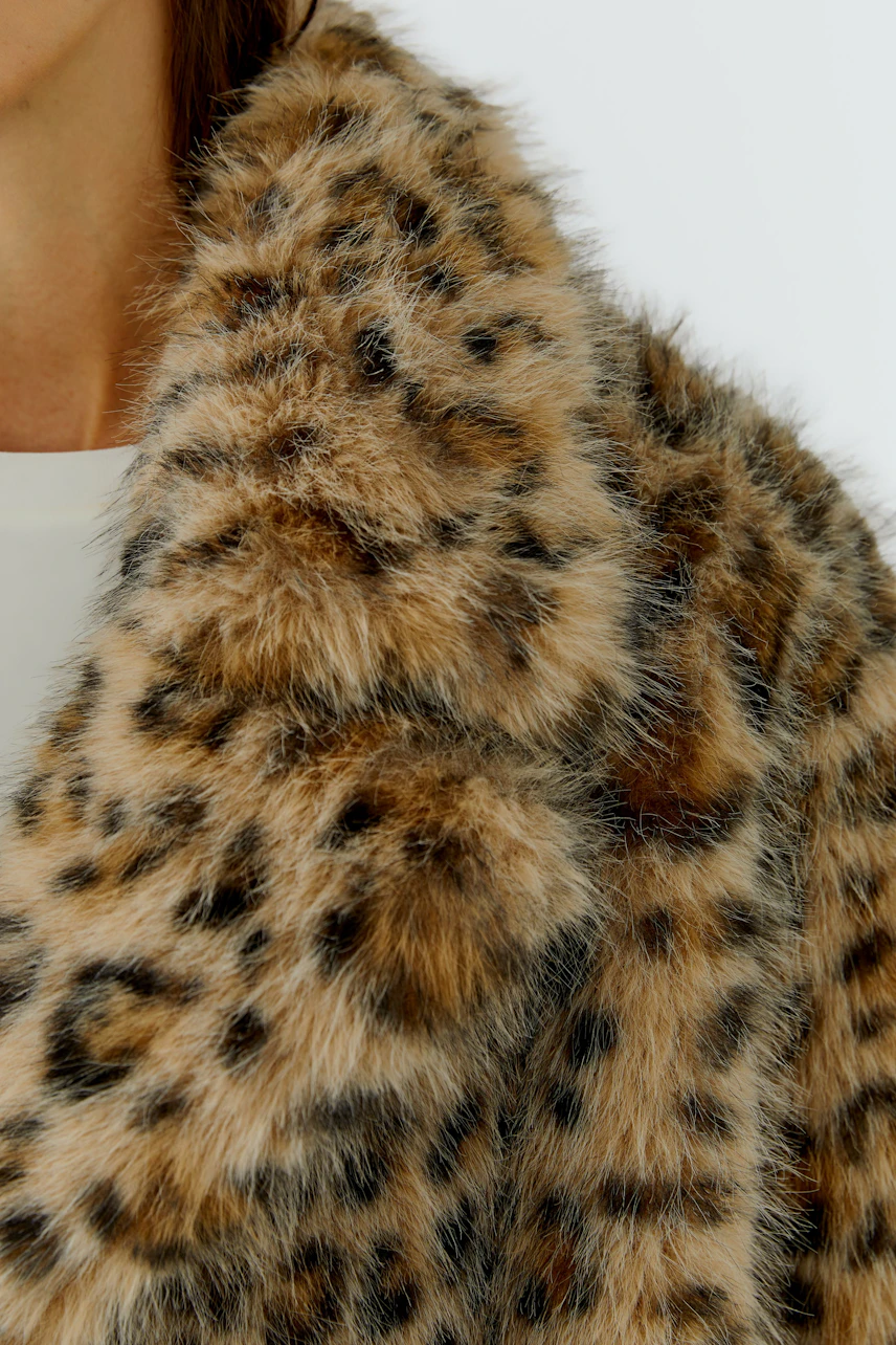 Frau in Outdoorjacke mit Leopardenmuster, flauschig und warm, ideal für kühle Tage.