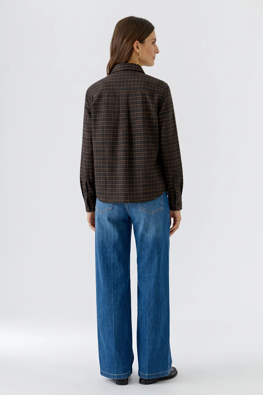 Frau in karierter Hemdbluse und blauer Jeans, Rückansicht. Lässiger Look für den Alltag.