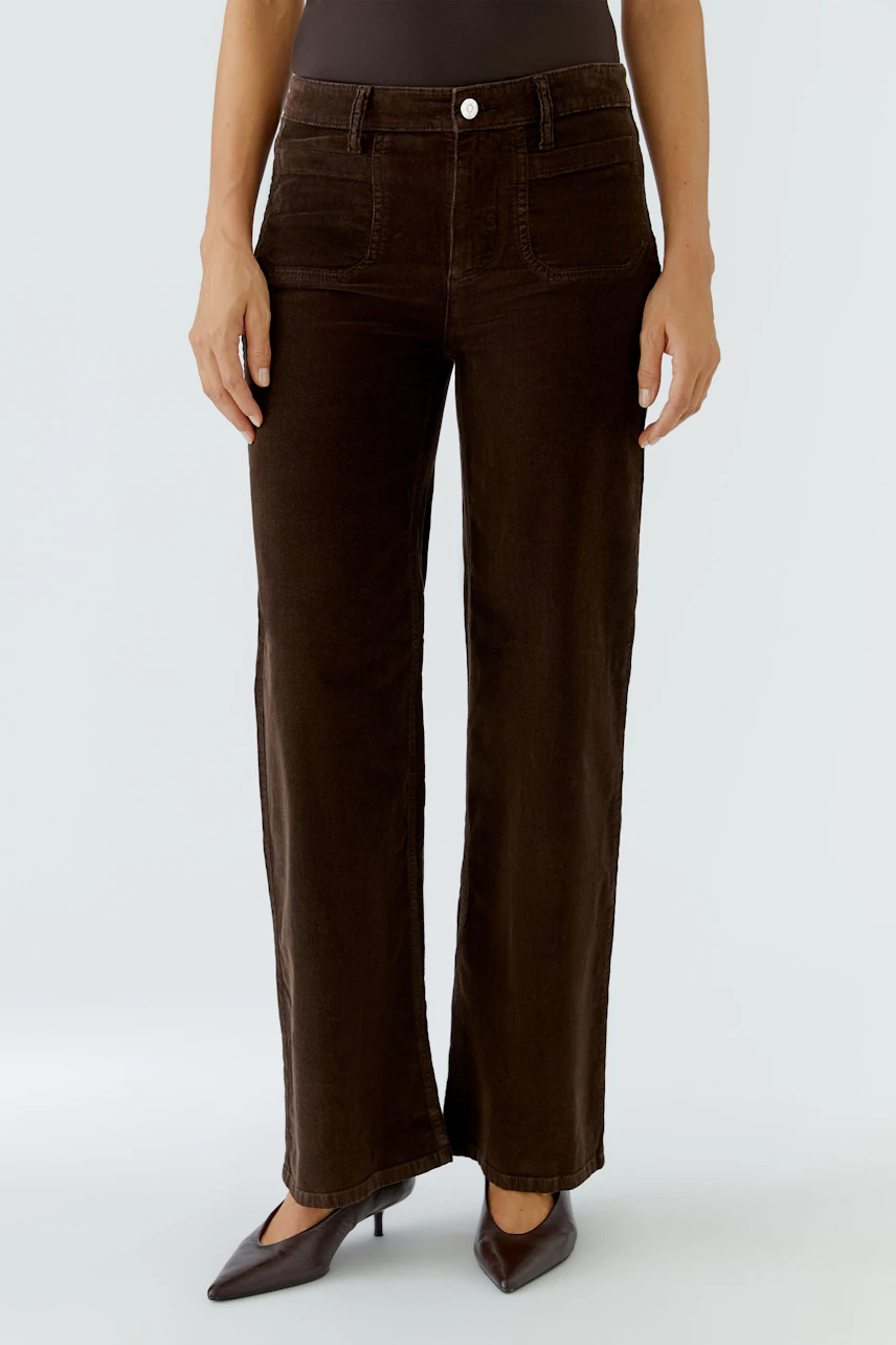 Braune Damen-Hose: Frau in brauner Cordhose mit weitem Bein und schlichtem Oberteil.
