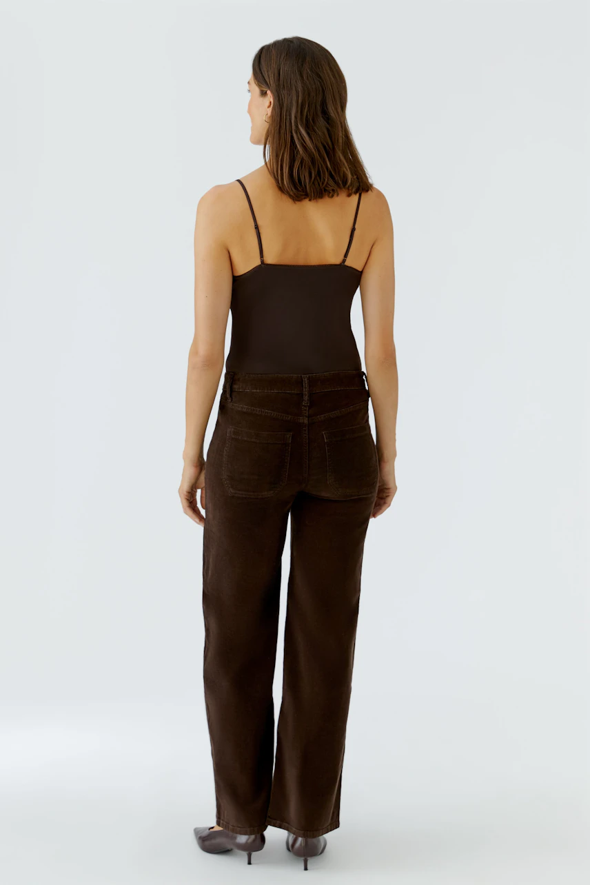 Braune Damen-Hose: Frau in lässiger, brauner Hose mit schmalen Trägern, von hinten gesehen.