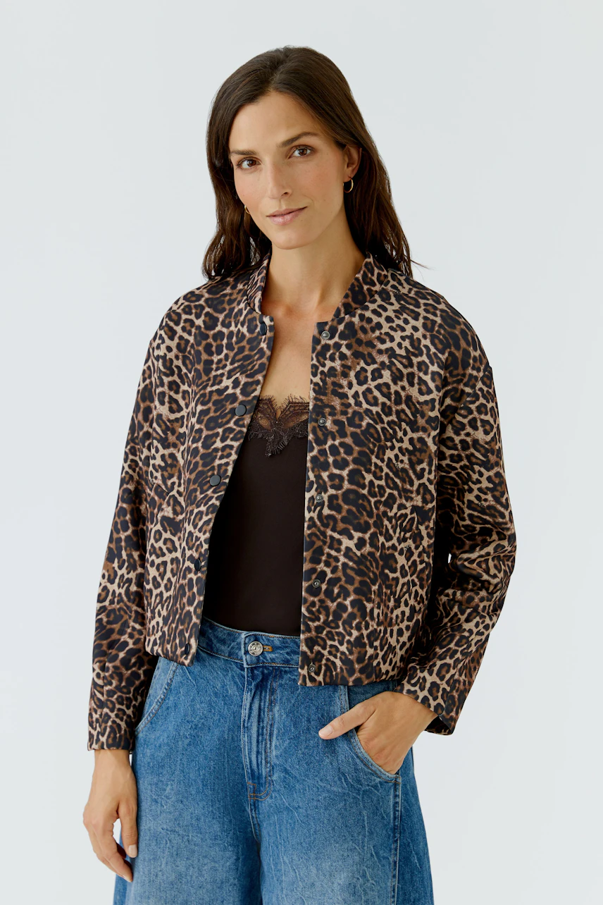Leopardenmuster-Jacke: Frau in lässiger Jacke mit Leopardenmuster, schwarzem Top und blauen Jeans.