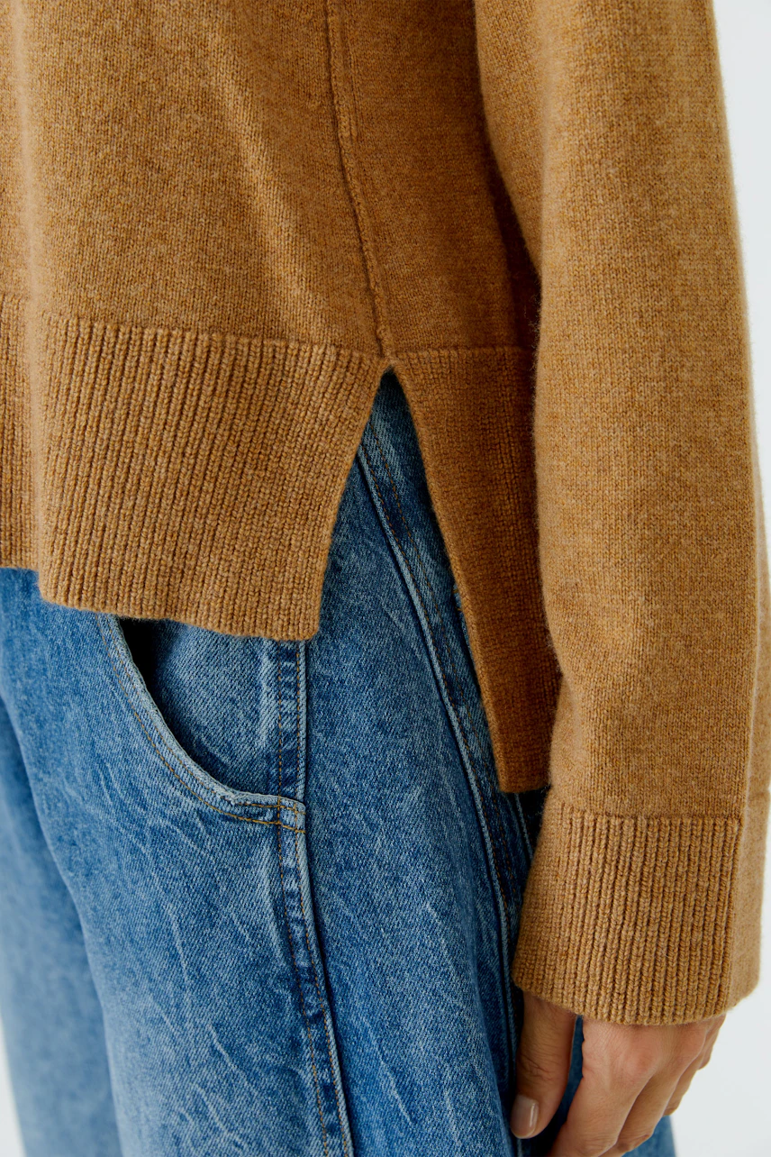 Lässiger Damen-Pullover: Frau trägt braunen Pullover mit Seitenschlitzen und blauer Jeans.