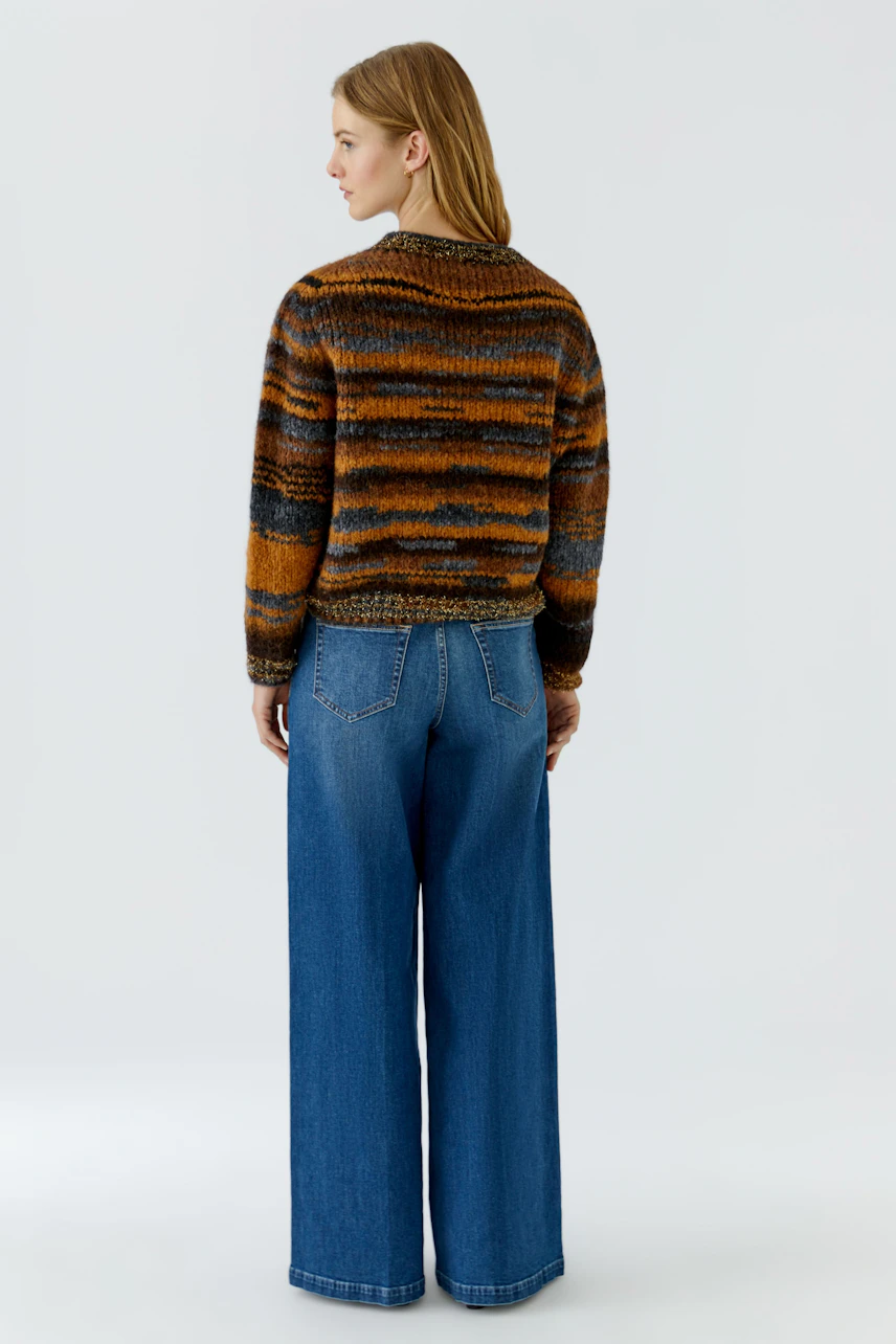 Frau im gestreiften Pullover, blickt zur Seite. Kombiniert mit blauer Jeans für einen lässigen Look.