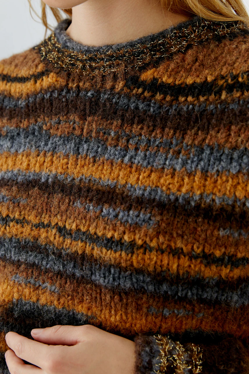 Frau im gestreiften Pullover in warmen Erdtönen, weiche Textur, lässiger Look.