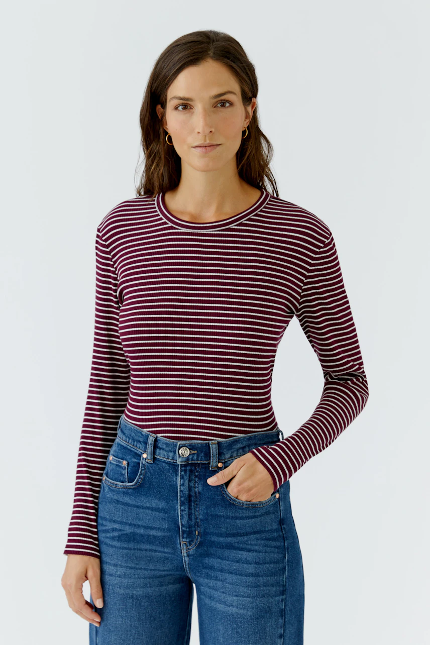 Gestreiftes Langarmshirt: Frau im rot-weiß gestreiften Shirt und blauer Jeans, lässig und modern.