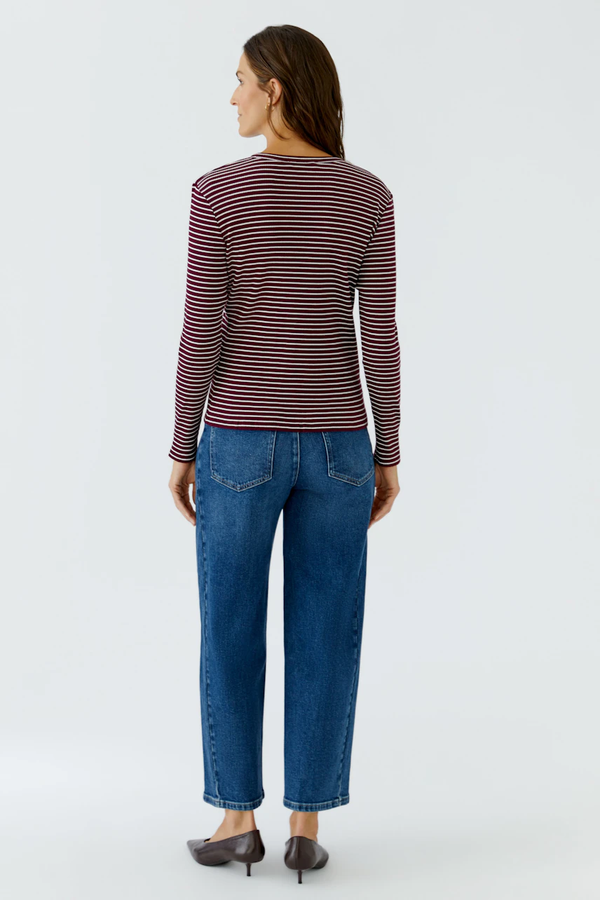 Gestreiftes Langarmshirt: Frau in rot-schwarz gestreiftem Shirt und blauer Jeans von hinten.