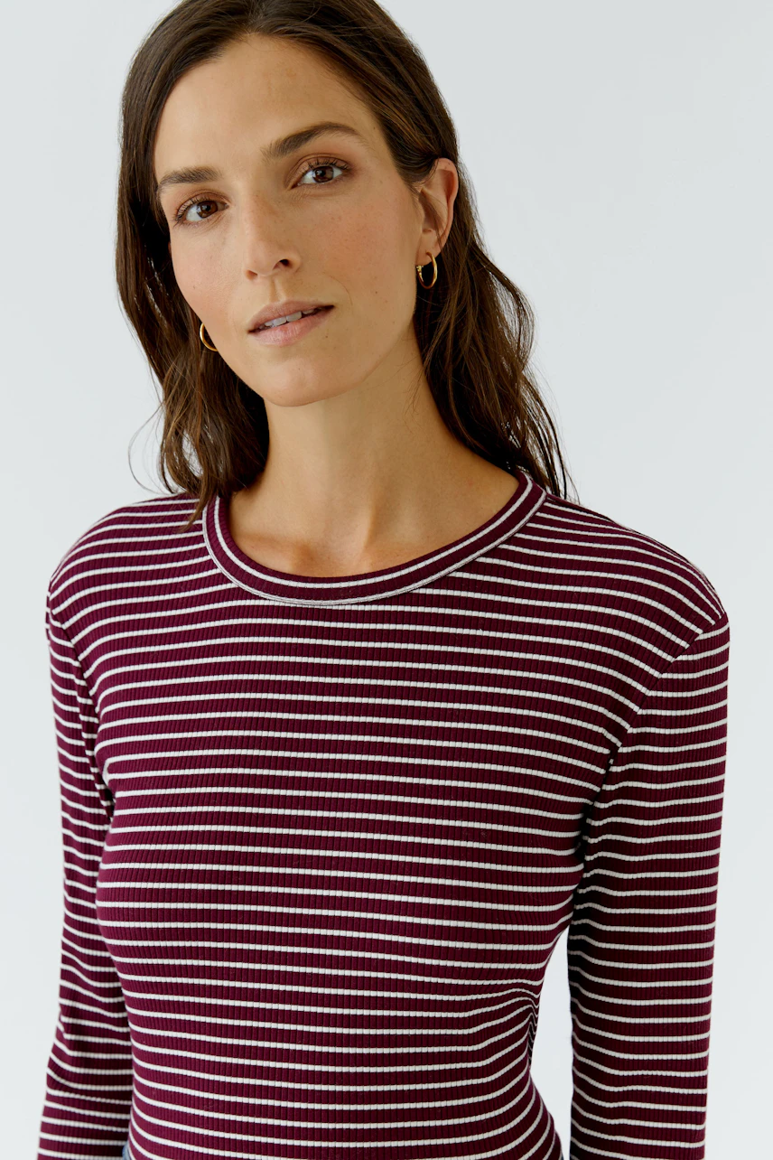 Gestreiftes Langarmshirt: Frau im weinroten Shirt mit weißen Streifen und Rundhalsausschnitt.