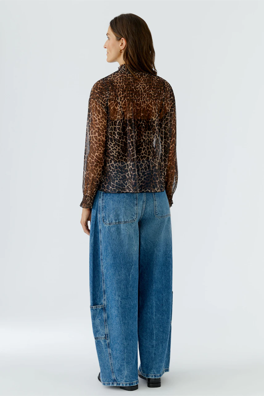 Woman in leopard print long-sleeve shirt and wide-leg jeans, viewed from the back.