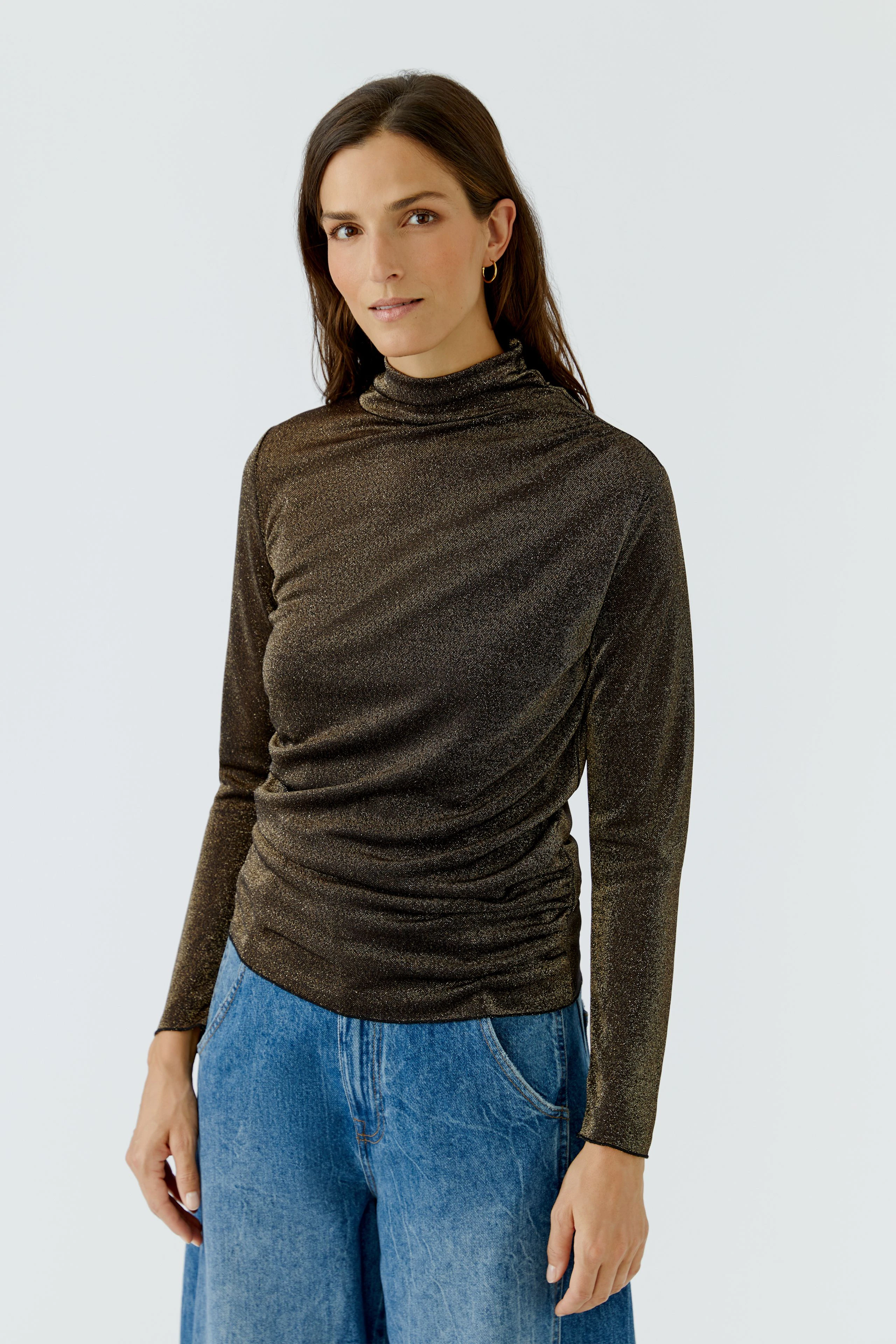 Casual long-sleeve shirt: Woman in a shimmering brown top with relaxed fit, paired with blue jeans.