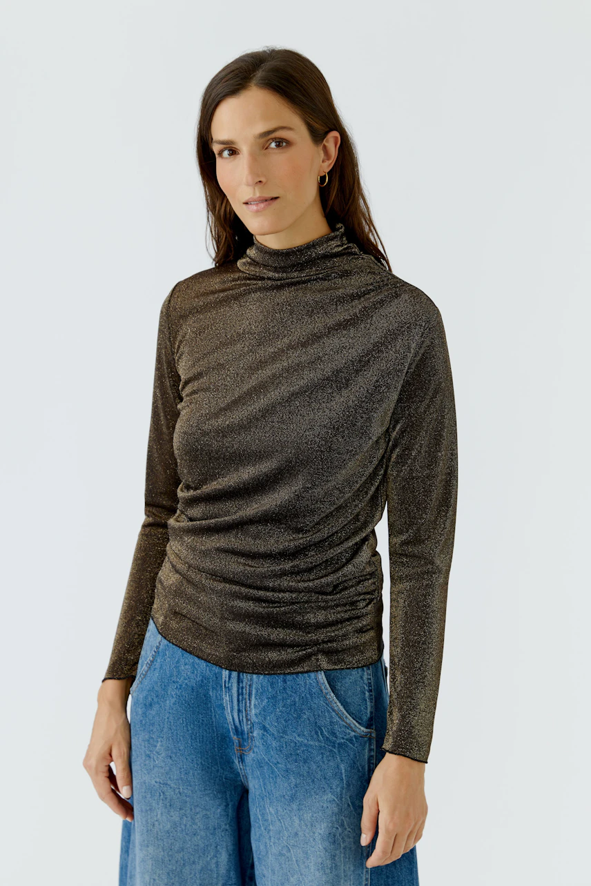 Casual long-sleeve shirt: Woman in a shimmering brown top with relaxed fit, paired with blue jeans.