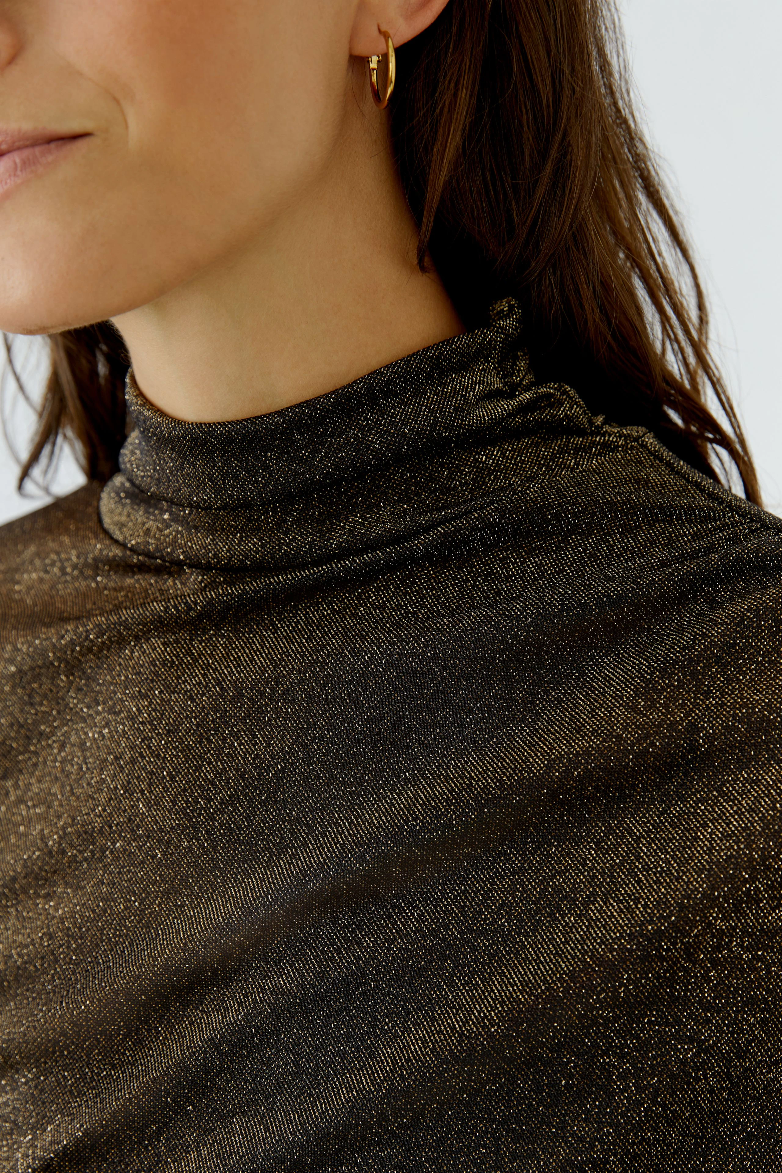 Woman in a shimmering long-sleeve shirt with a high collar, showcasing a chic and modern style.